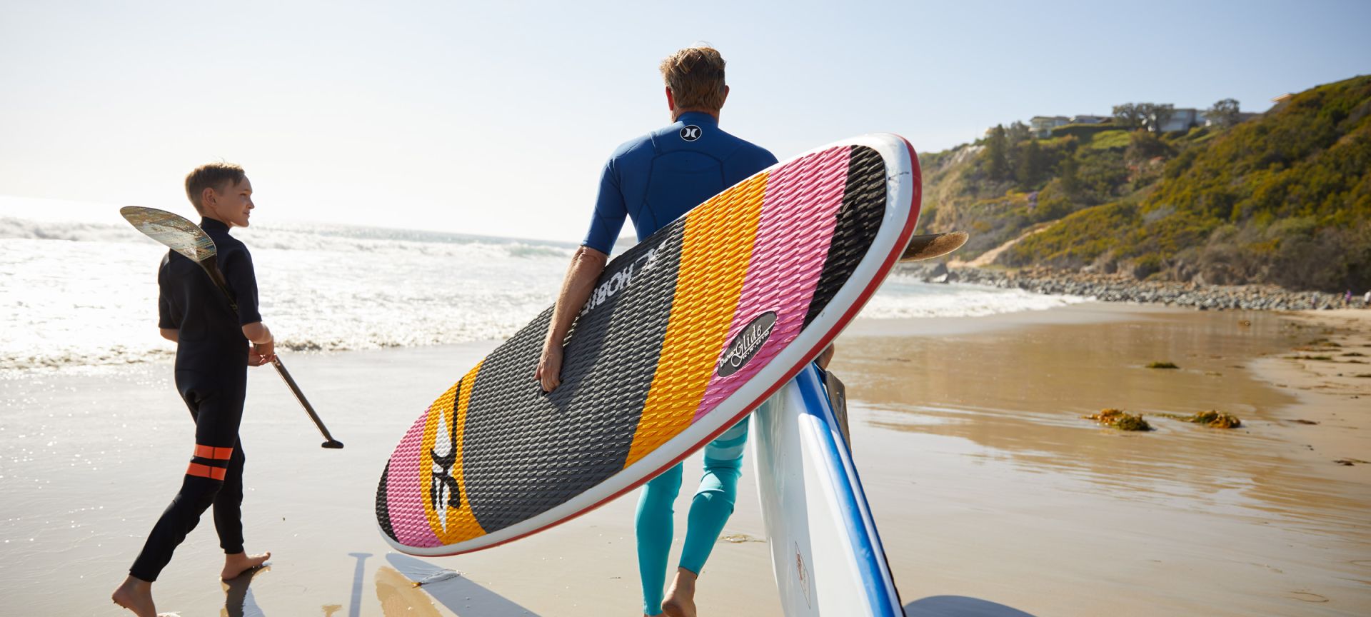 A Man Carrying A Surf Board On A Beach